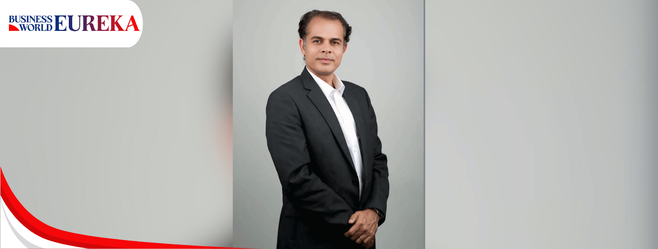Navneet Bali standing confidently in a formal black suit against a neutral background.